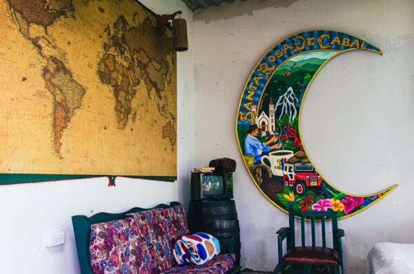 Colorful crescent mural and vintage furniture in Casa Santa Rosa garden lodge, showcasing local charm in Santa Rosa de Cabal, Risaralda.