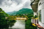 Yellow bridge spans the river, surrounded by lush green hills and a cloudy sky in Tolima, Colombia.