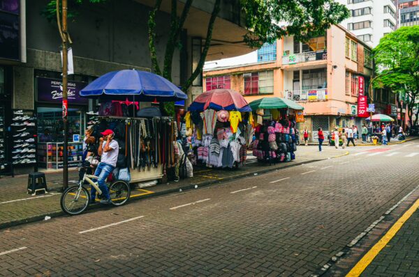 Vibrant market stalls line the street in Pereira, Risaralda, Colombia, with colorful umbrellas and local vendors bustling.