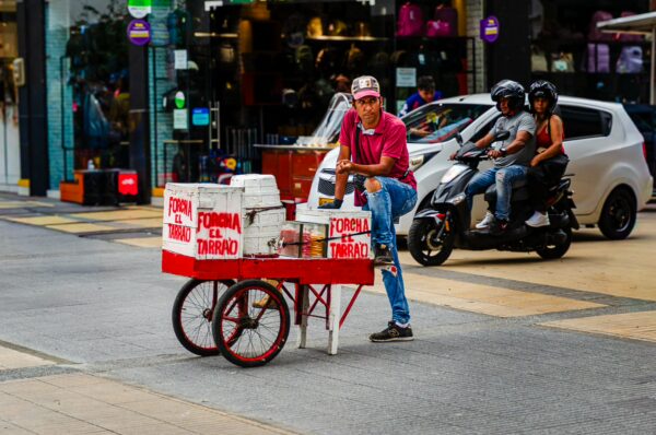 Colorful street scene featuring a vendor with a cart, selling snacks on carrera 14 in Armenia, Quindio, Colombia.
