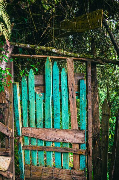 Vibrant turquoise wooden gate amidst lush greenery in Murillo, Tolima, Colombia, inviting exploration of the natural surroundings.