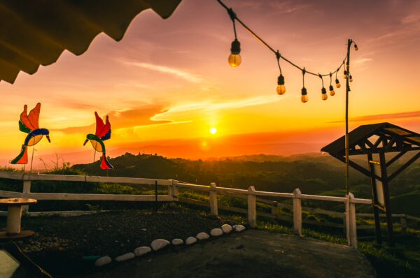 Colorful wind chimes sway against a vibrant sunset at Mirador Colina Iluminada, Filandia, Quindío, Colombia.