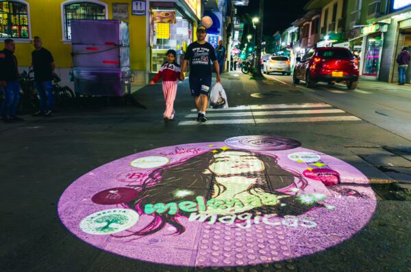 Vibrant street art featuring a woman's portrait in pink hues, illuminating the lively nightlife of Santa Rosa de Cabal, Risaralda, Colombia.