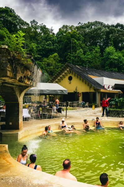 Relaxing visitors enjoy the thermal waters at Termales de Santa Rosa, surrounded by lush greenery in Risaralda, Colombia.