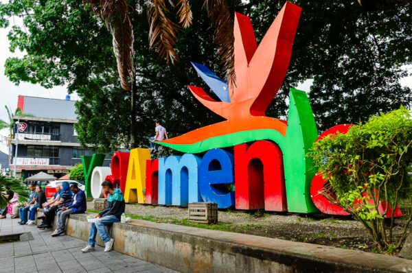 Colorful "Yo Armenia" sign in Parque Sucre, with visitors sitting nearby amidst lush greenery in Armenia, Quindío, Colombia.
