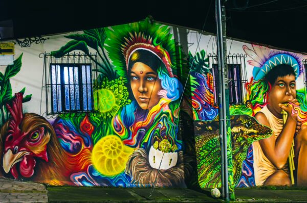 Vibrant street mural in Santa Rosa de Cabal, Colombia, featuring colorful depictions of people, animals, and foliage.