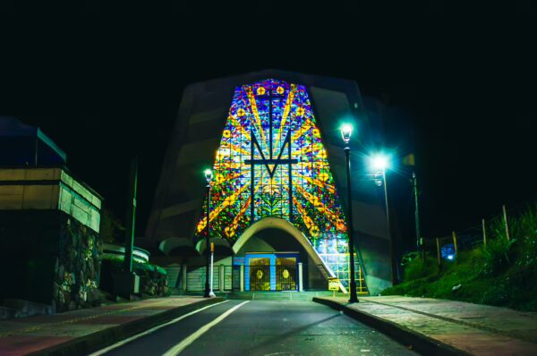 Vibrant stained glass illuminates the entrance of Santuario de la Milagrosa in Santa Rosa de Cabal, Risaralda, Colombia, at night.