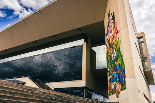 Vibrant mural on the exterior of a modern building, showcasing colorful art against a backdrop of blue skies in Pereira, Risaralda, Colombia.
