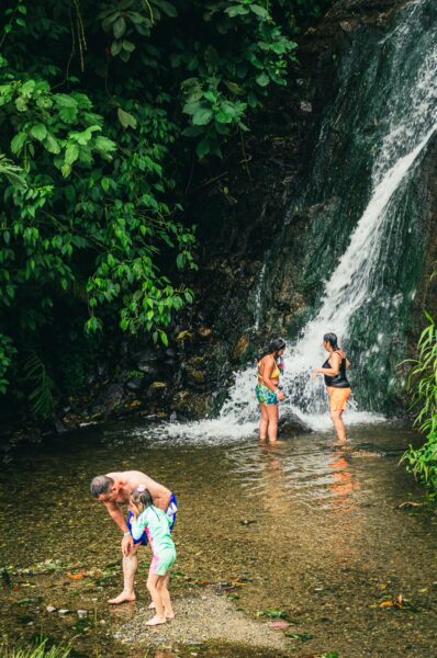 Families enjoy a refreshing moment in the clear waters near the Rosa Thermal Springs amidst lush green foliage in Risaralda, Colombia.