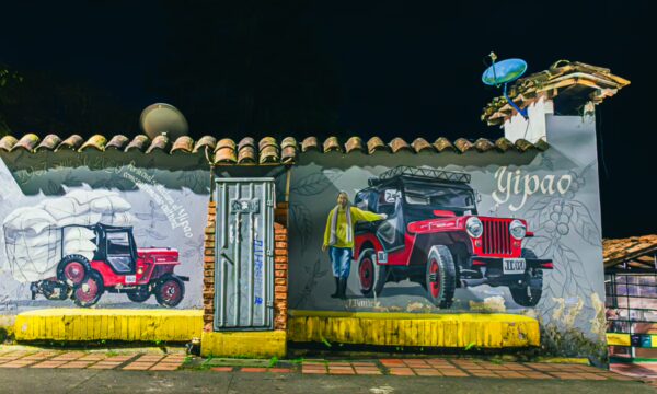 Colorful murals of vintage jeeps decorate a brick wall in Santa Rosa de Cabal, showcasing the town's vibrant culture and heritage.