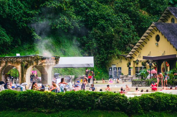 Relaxing visitors enjoy the steaming thermal waters surrounded by lush greenery at Termales de Rosa in Risaralda, Colombia.