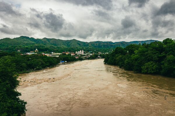 Flowing brown waters of Río Magdalena surrounded by lush greenery and mountainous backdrop in Honda, Tolima, Colombia.
