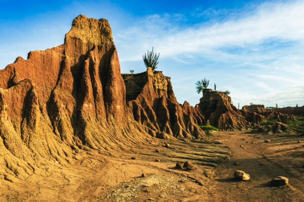 Labyrinthine rock formations with reddish hues and sparse vegetation in Tatacoa Desert, Huila, Colombia. Blue skies above.