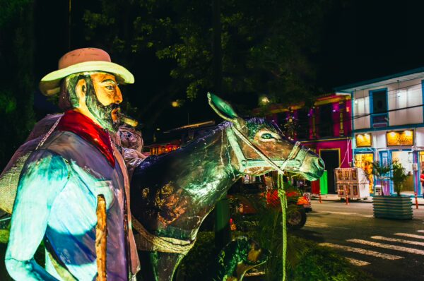 Colorful sculpture of a man with a horse, illuminated at night in Parque Bolivar, Filandia, Quindio, Colombia.