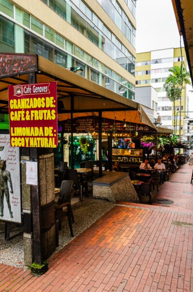 Lively street scene in Quindío, Colombia, featuring colorful cafes, a vibrant market, and pedestrians enjoying the atmosphere.