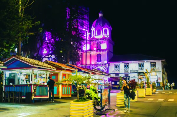 Vibrant night scene at Parque Bolívar in Filandia, Quindío, Colombia, featuring colorful stalls and illuminated architecture.