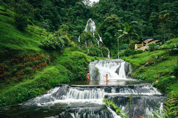 Serene thermal springs cascade down rocky tiers in Risaralda, Colombia, surrounded by lush greenery and vibrant foliage.