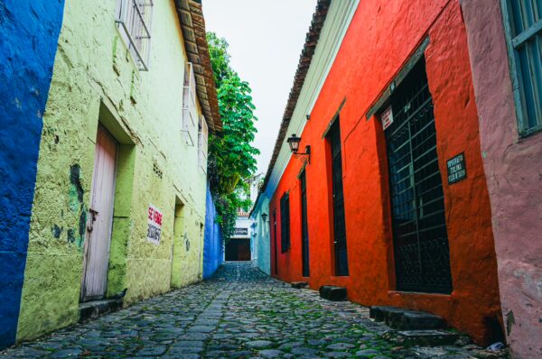 Colorful buildings line a cobblestone street in Honda, Tolima, Colombia, showcasing vibrant yellow, red, and green facades.