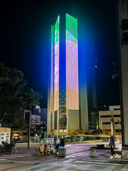 Colorful towers illuminated at night near Gobernación de Quindío, Armenia, Colombia, showcasing vibrant city life and modern architecture.