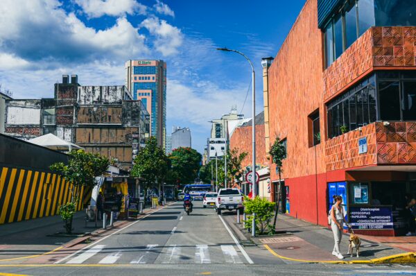 Vibrant street scene in Pereira, Risaralda, Colombia, featuring colorful buildings, traffic, and a clear blue sky.