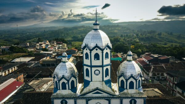 The blue and white dome of Inmaculada Concepción church rises above a lush landscape in Filandia, Quindio, Colombia.