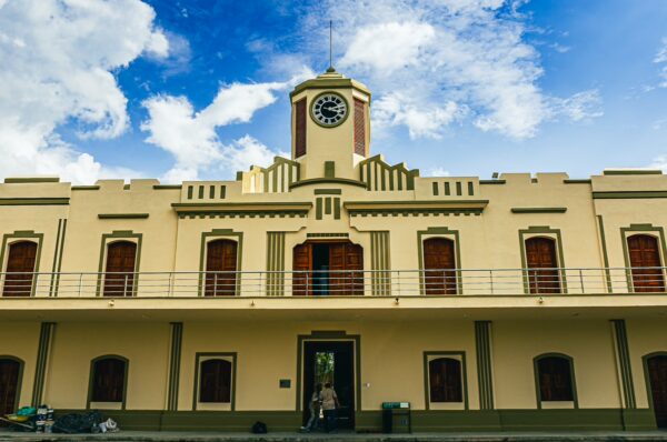 Crisp blue skies frame the historic clock tower of a yellow and green building in Pereira, Risaralda, Colombia.