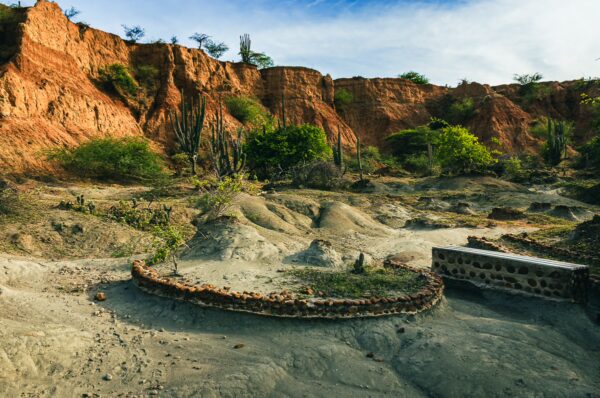 Cactus-studded terrain features reddish cliffs and dry riverbeds in the Tatacoa Desert, Huila, Colombia.