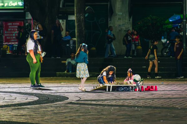 Children play on a plaza in Pereira, Risaralda, Colombia, with colorful toys and a lively atmosphere at night.