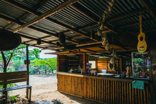 La Guaca hotel features a rustic wooden bar with colorful decor, surrounded by greenery in the Tatacoa Desert, Huila, Colombia.