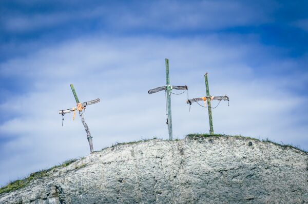 Weathered crosses stand atop a hillside in Tatacoa Desert, Huila, Colombia, contrasting against a vivid blue sky.