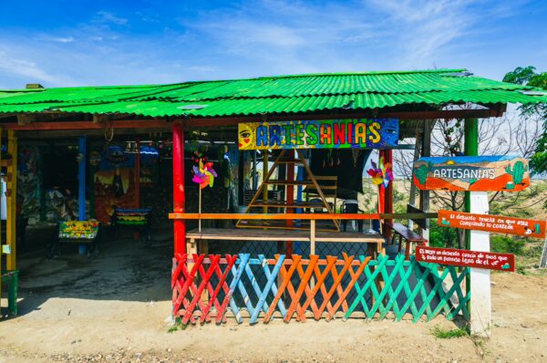 Colorful artisan shop in the Tatacoa Desert, Huila, Colombia, features vibrant decor and a green corrugated roof.