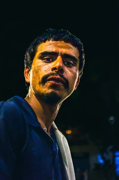 Portrait of a man with a serious expression, wearing a dark shirt against a dimly lit background in Pereira, Risaralda, Colombia.