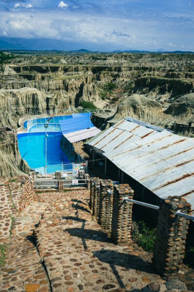 Vibrant blue pool nestled in the unique landscape of Los Hoyos, Tatacoa Desert, Huila, Colombia, with rocky formations and steps.