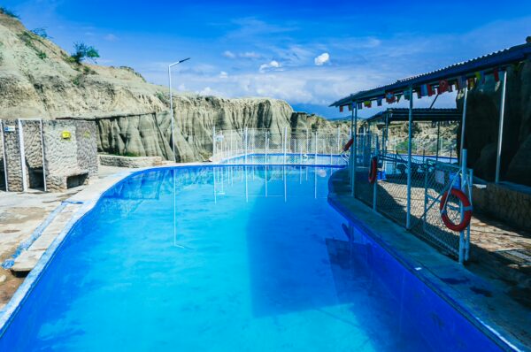 A serene blue swimming pool surrounded by the striking landscapes of the Tatacoa Desert in Huila, Colombia.