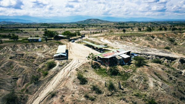 Vast Tatacoa Desert in Huila, Colombia, featuring rugged terrain, scattered greenery, and a distant view of rolling hills.