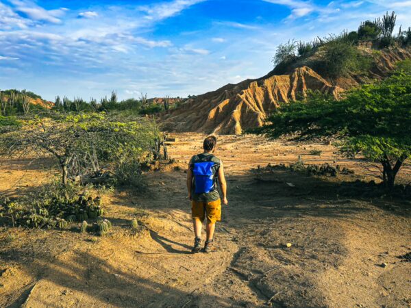 Exploring the striking landscape of Tatacoa Desert in Huila, Colombia, with rugged terrain and vibrant vegetation under a blue sky.