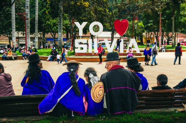 Colorful "Yo Amo Silvia" sign in Parque Principal, with locals in traditional attire enjoying the vibrant atmosphere in Cauca, Colombia.