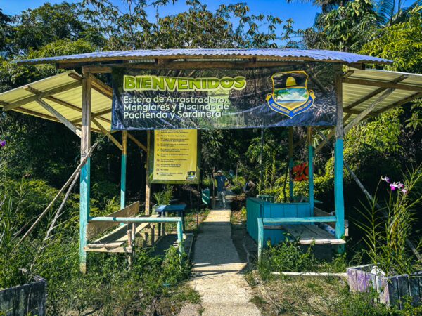Natural pool entrance in Ladrilleros features colorful signage welcoming visitors with lush greenery in Valle del Cauca, Colombia.