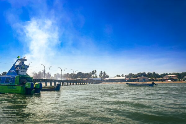 Vibrant green boat near a pier in Juanchaco, Valle del Cauca, Colombia, with clear blue skies and calm waters.