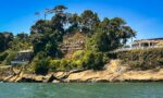 Maguipi features a lush, green hillside with a sign and a coastal view along Valle del Cauca, Colombia.