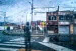 Raindrops blur the view of a street in Pasto, Nariño, Colombia, featuring traffic signage and nearby buildings.