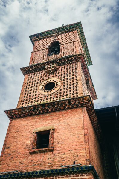Iglesia de San Francisco's intricately patterned brick tower rises against a cloudy sky in Cali, Valle del Cauca, Colombia.