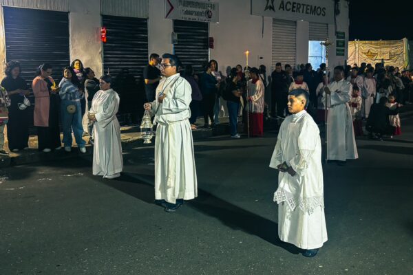 Participants dressed in white garments stand in a festive street procession in Popayán, Cauca, Colombia, surrounded by onlookers.