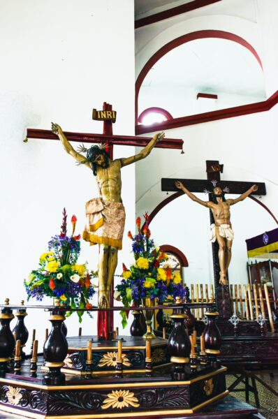 Nuestra Señora del Perpetuo Socorro features a detailed crucifix atop an ornate altar, surrounded by vibrant flowers in Silva, Cauca, Colombia.