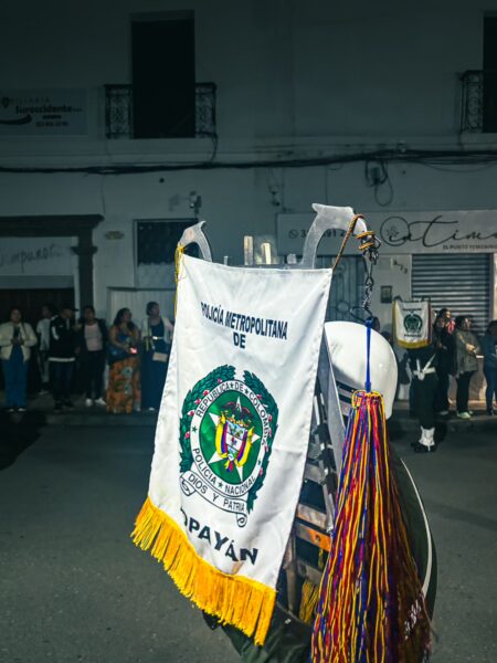 Colorful banners and a festive atmosphere highlight a night scene in Popayán, Cauca, showcasing local traditions.