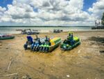 Colorful boats lined up on the sandy shore of Buenaventura, Valle del Cauca, Colombia, against a backdrop of puffy clouds.