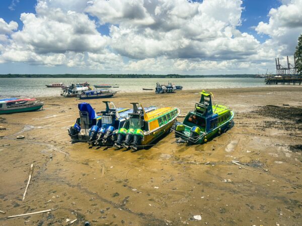 Colorful boats lined up on the sandy shore of Buenaventura, Valle del Cauca, Colombia, against a backdrop of puffy clouds.