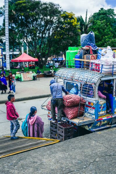 Vibrant scene in Parque Principal Silva, Cauca, Colombia, with a colorful truck loaded with goods and people engaged in lively activities.