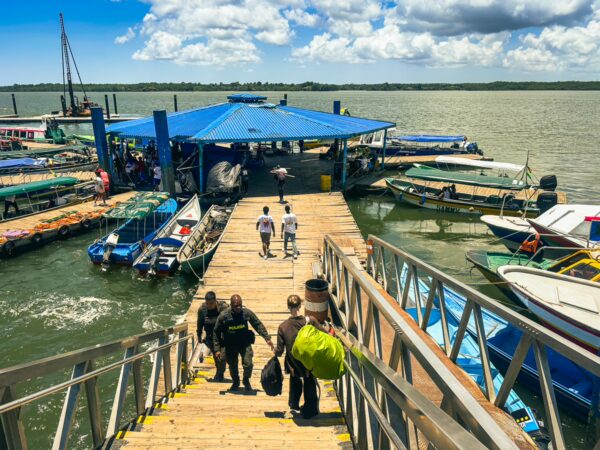 Colorful boats line the dock as travelers walk down the wooden pier in Buenaventura, Valle del Cauca, Colombia.