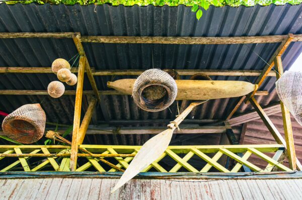 Traditional woven baskets and a wooden paddle hang from the rustic ceiling of a structure in Juanchaco, Valle del Cauca, Colombia.